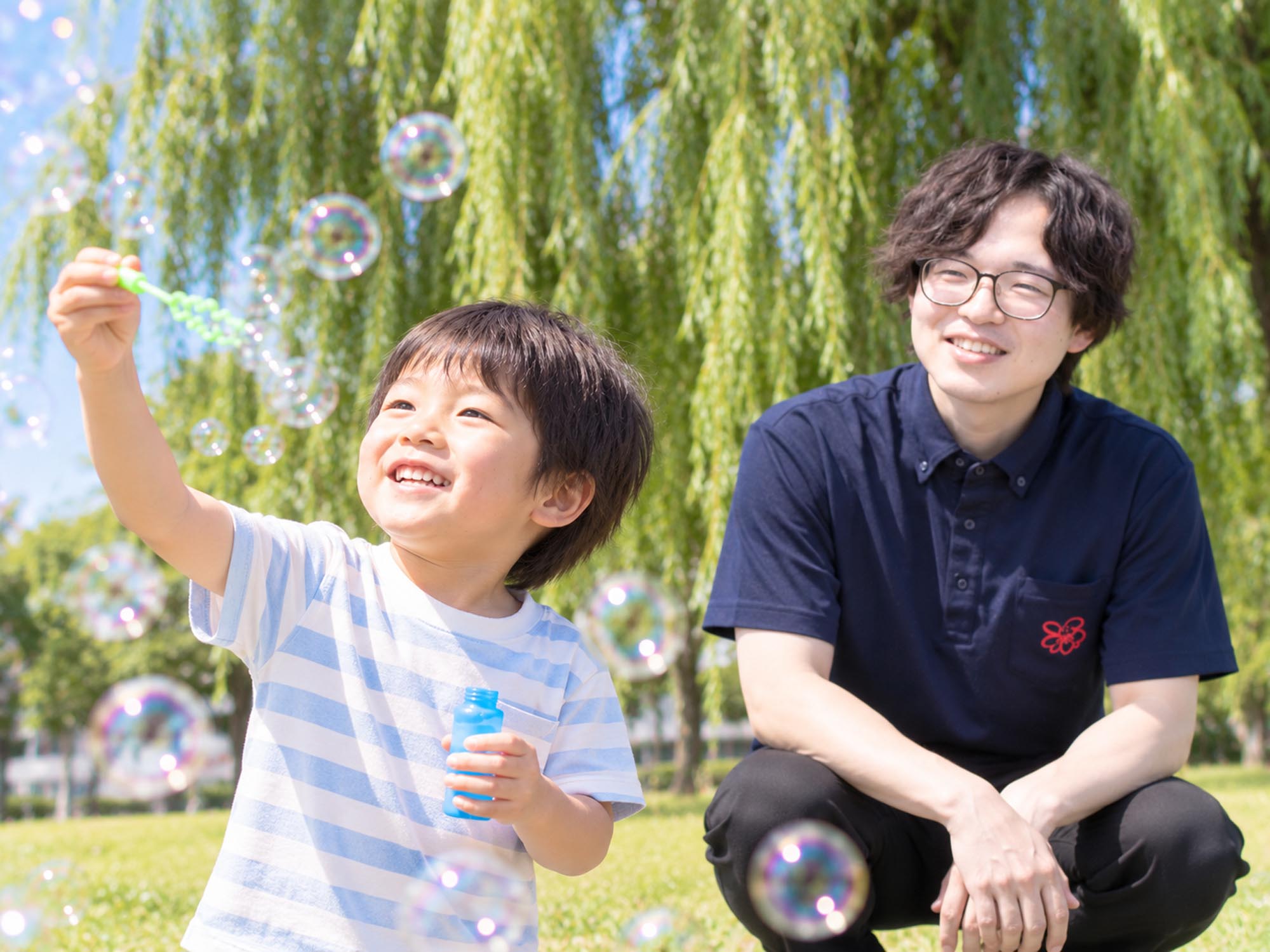 子どもの活動を少し離れた場所から見守るスタッフ
