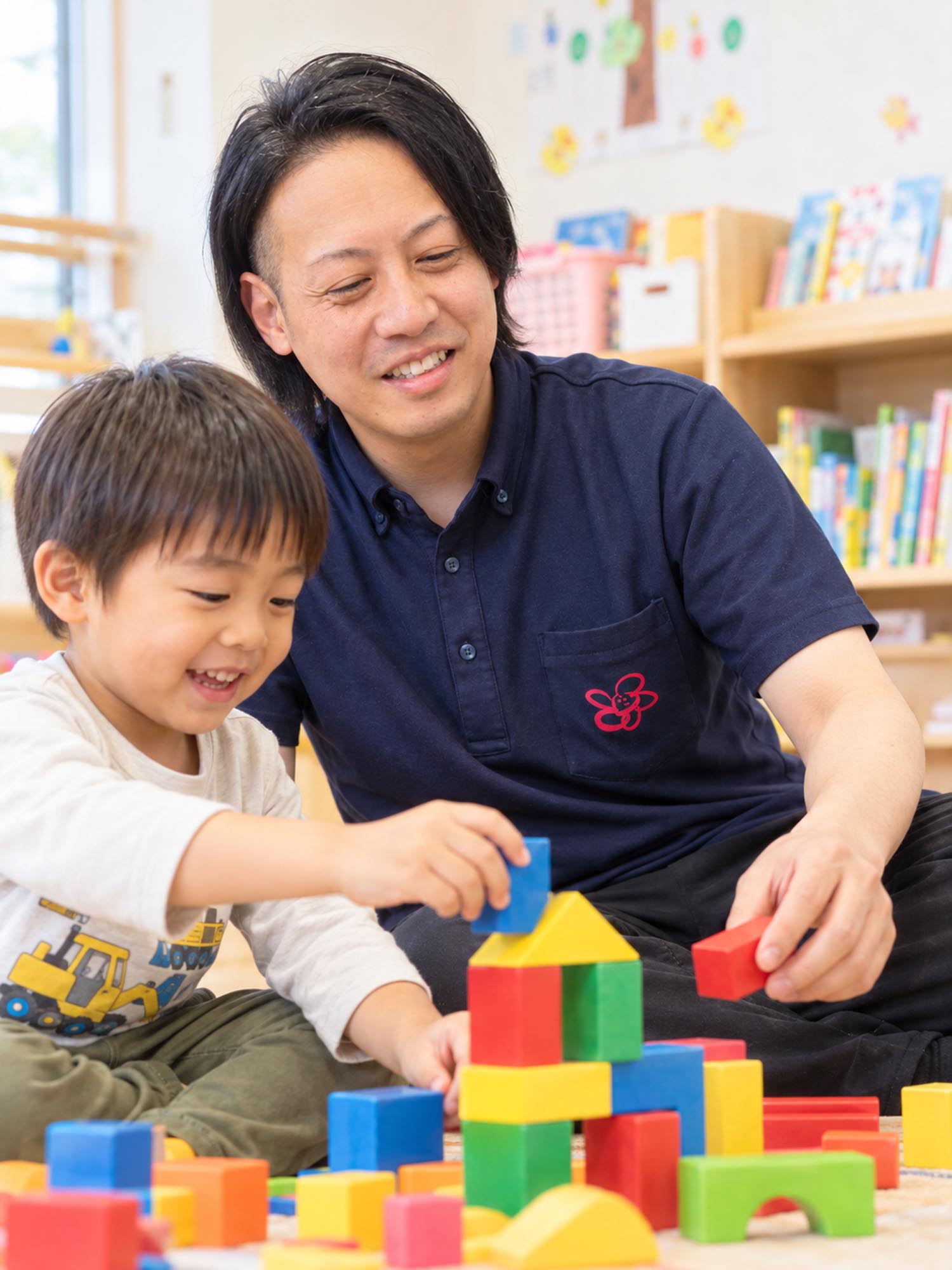 子どものそばで一緒に積み木遊びをするスタッフ